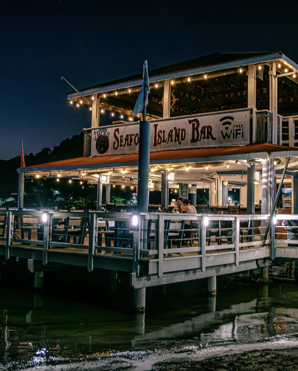 Captain Jack's Seafood Island Bar lit up at night over the Caribbean Sea