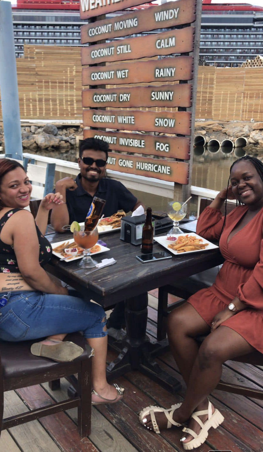 Happy guests dining on Captain Jack's patio with cruise ship in background